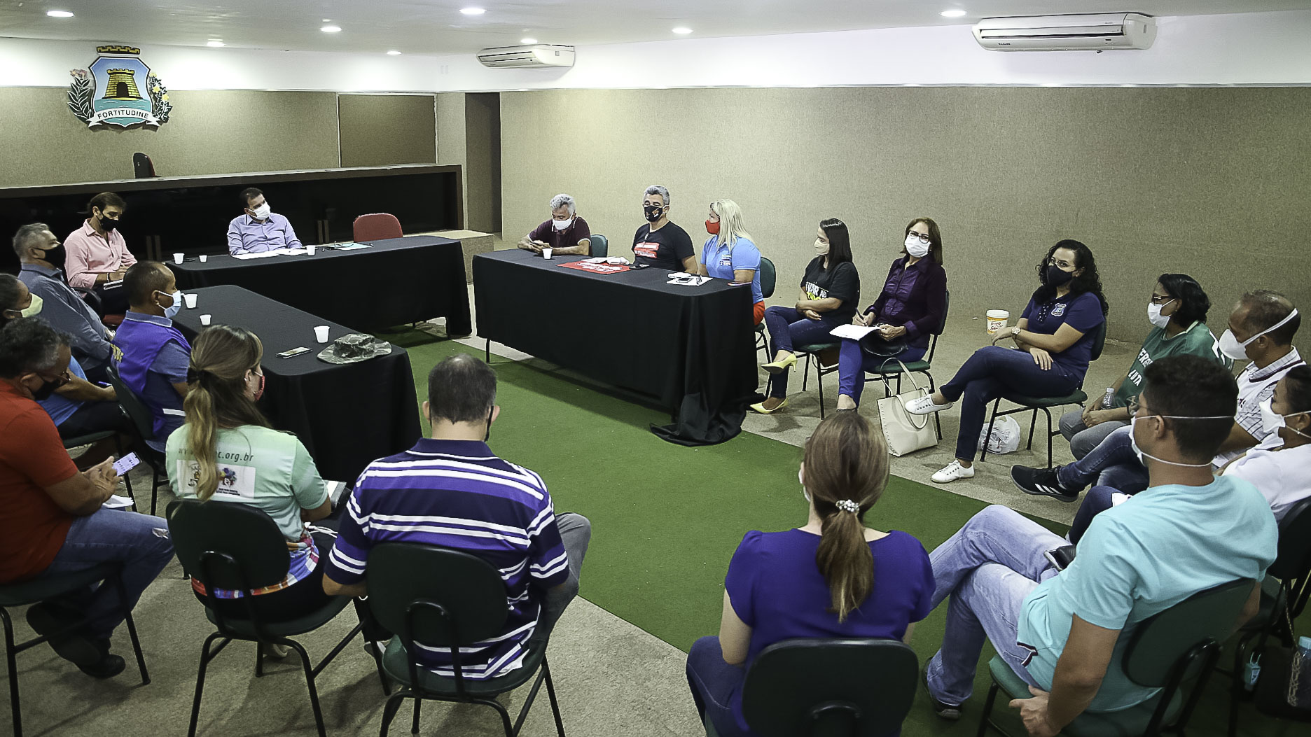 grupo de pessoas sentadas em uma roda de cadeiras dentro de um auditório